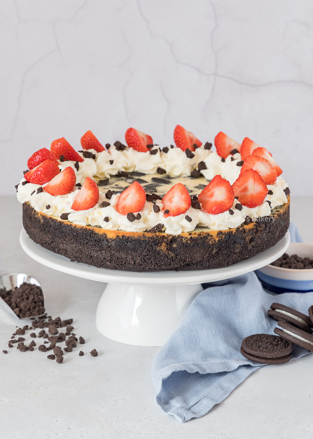 Oreo cheesecake op taartplateau met topping van slagroom en aardbeien