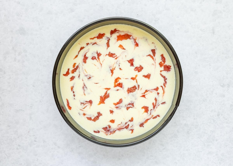 Bereid het cheesecakebeslag en stort op de bakvorm. Schep de compote erop en swirl erdoor.