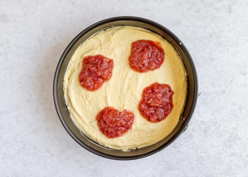 Stort het beslag de springvorm, schep de compote erop en swirl er doorheen.