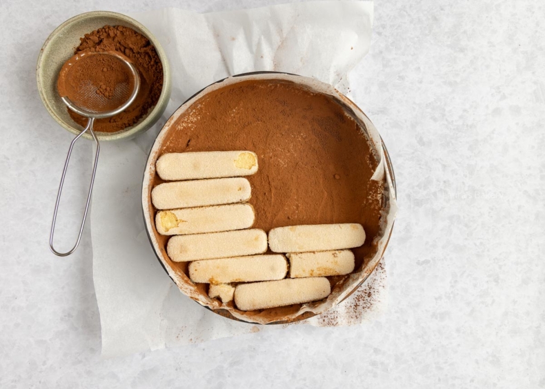 Het mascarpone mengsel bedekken met cacaopoeder en daarna met lange vingers