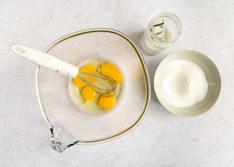 Neem een tweede kom en mix hierin de eieren, kristalsuiker en vanillesuiker in enkele minuten tot een romig mengsel.