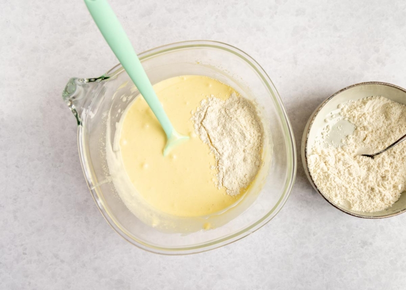 Spatel in delen het zelfrijzend bakmeel en zout door het ei-slagroom mengsel.