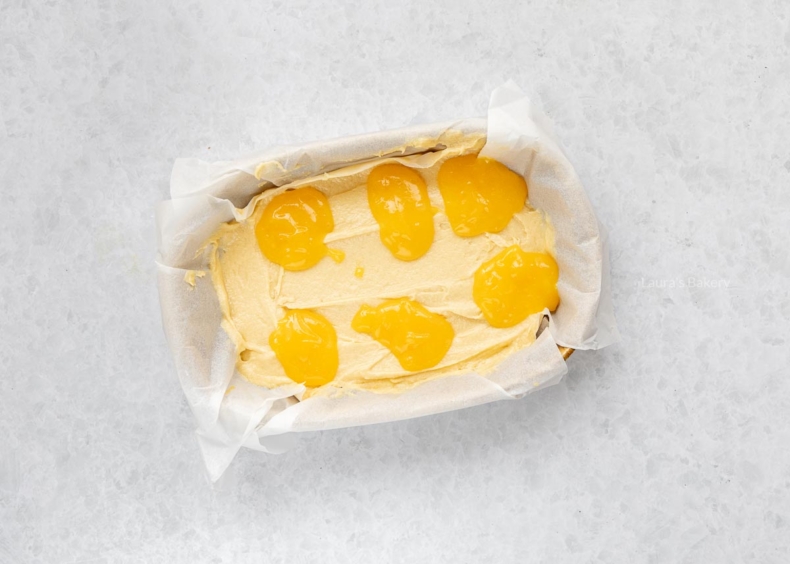 Stort het beslag in de bakvorm en verdeel 6 hoopjes lemon curd erover.