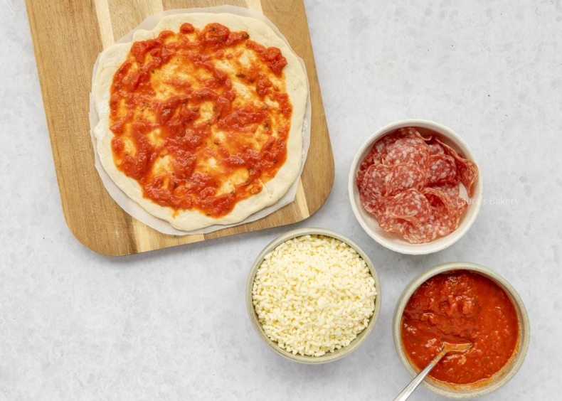 Rol het deeg mooi dun uit en beleg dun met tomatensaus.