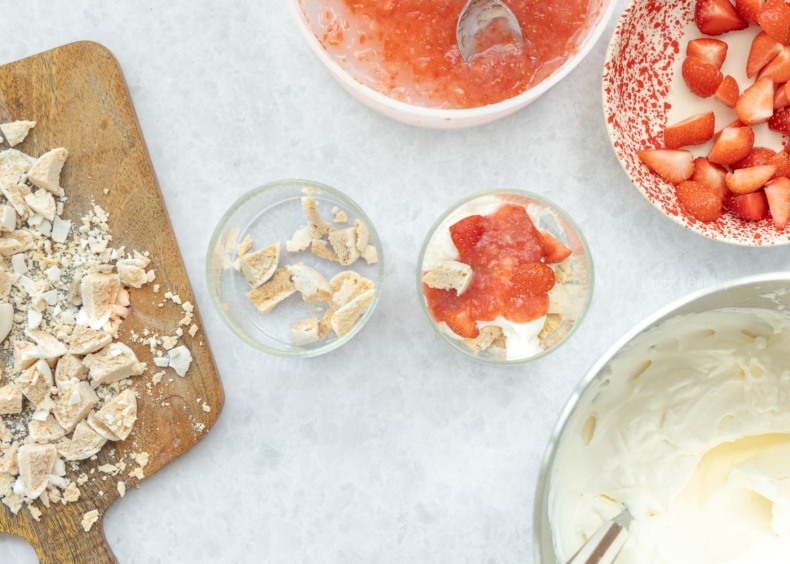 Vul de dessertglaasjes met de slagroom, aardbeien en meringue